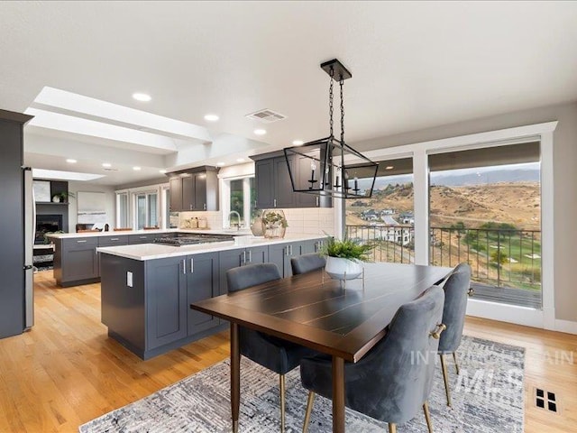 kitchen featuring light hardwood / wood-style flooring, tasteful backsplash, decorative light fixtures, and kitchen peninsula