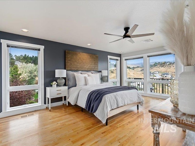 bedroom with ceiling fan, multiple windows, and hardwood / wood-style floors