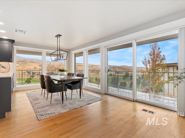 dining space with light hardwood / wood-style flooring, a mountain view, and an inviting chandelier