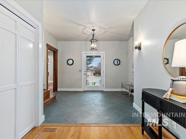 entryway featuring baseboards, wood finished floors, and visible vents
