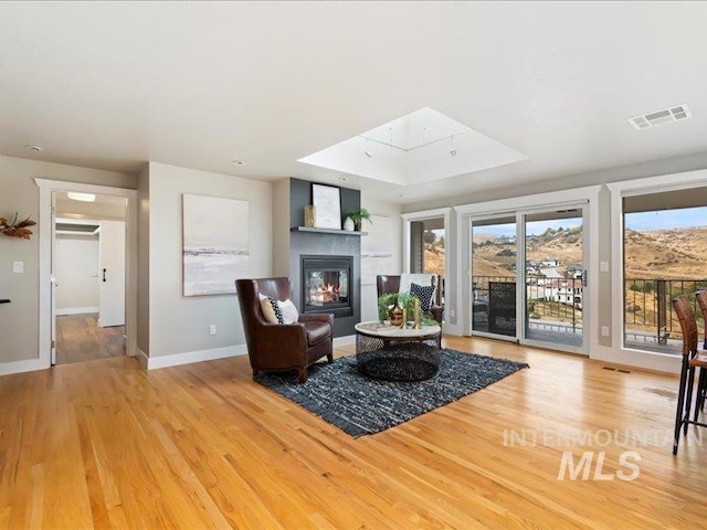 living room with light hardwood / wood-style flooring, a tray ceiling, and a skylight