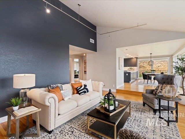 living area featuring light wood-style flooring, baseboards, and high vaulted ceiling