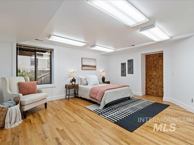 bedroom featuring light wood finished floors, baseboards, and visible vents