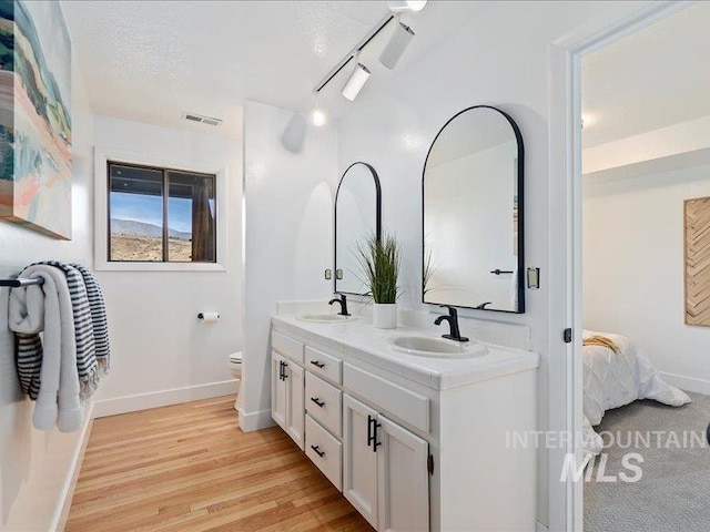 bathroom featuring track lighting, toilet, hardwood / wood-style floors, vanity, and a textured ceiling