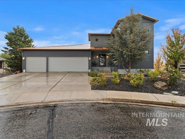 view of front of property featuring an attached garage, driveway, and metal roof