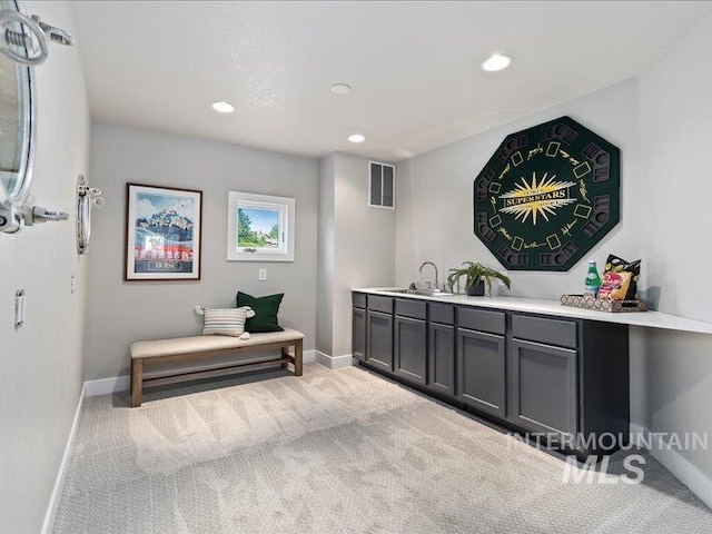 interior space with gray cabinets, sink, and light colored carpet