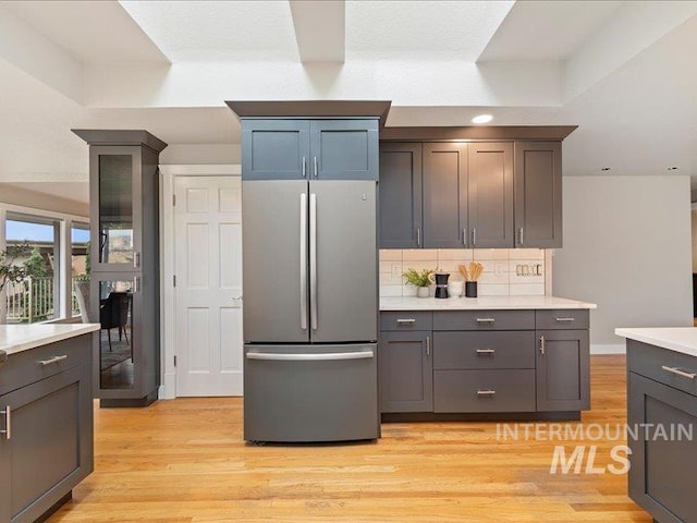 kitchen with light countertops, light wood-style flooring, freestanding refrigerator, and backsplash