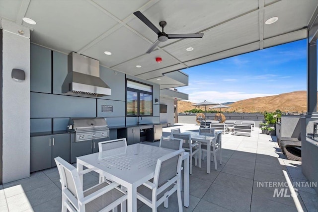 view of patio with an outdoor kitchen, ceiling fan, a mountain view, sink, and a grill