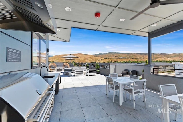 view of patio / terrace featuring ceiling fan, a mountain view, and area for grilling