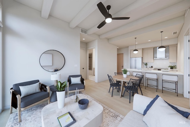 living room with beam ceiling, ceiling fan, and light hardwood / wood-style flooring