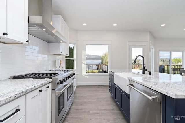 1910 W Campo Ln, Eagle, ID 83616 - kitchen with stainless steel appliances, wall chimney range hood, a sink, white cabinetry, and recessed lighting