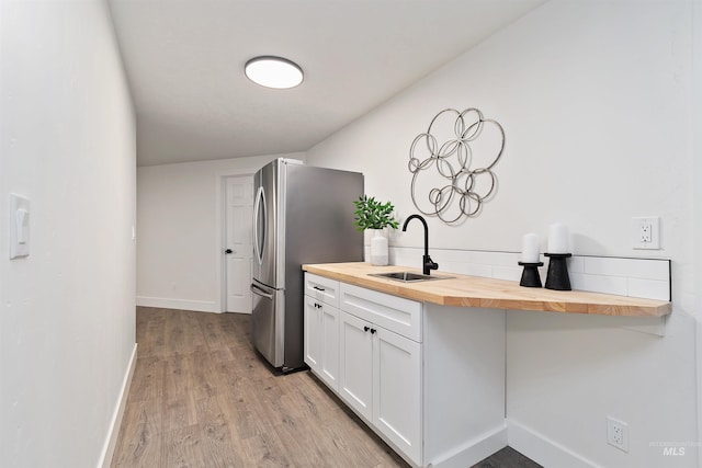 1910 W Campo Ln, Eagle, ID 83616 - kitchen with butcher block counters, a sink, baseboards, light wood finished floors, and white cabinets