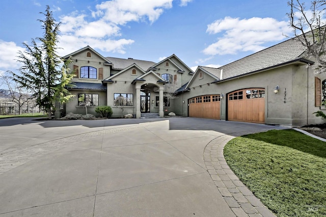 view of front facade with a garage, driveway, and stucco siding