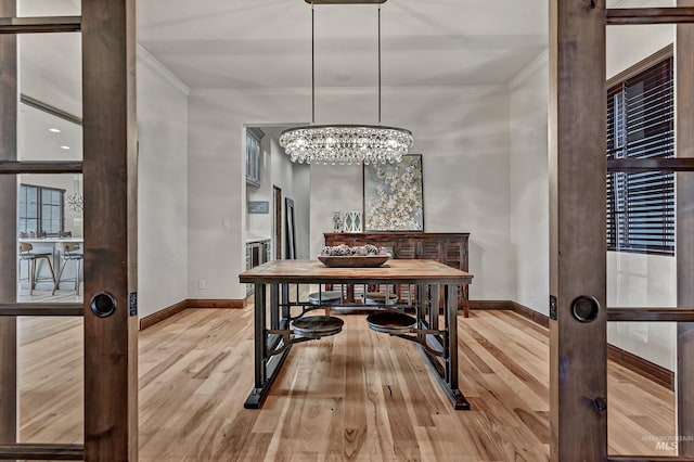 dining space featuring a notable chandelier, crown molding, baseboards, and wood finished floors