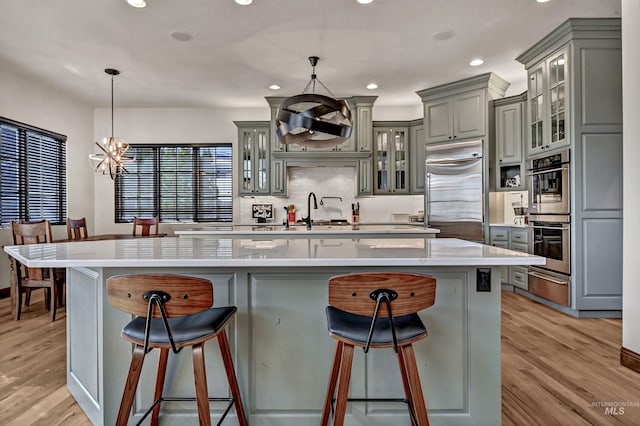 kitchen with gray cabinets, appliances with stainless steel finishes, light wood-type flooring, and a warming drawer