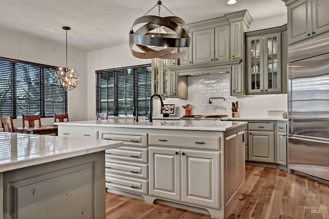 kitchen with a kitchen island with sink, built in fridge, gray cabinets, and light wood finished floors