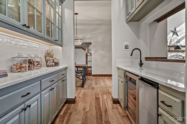 kitchen with light wood-style flooring, gray cabinets, a sink, tasteful backsplash, and wine cooler