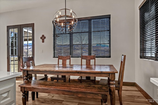 dining area featuring light wood-style flooring, french doors, baseboards, and an inviting chandelier