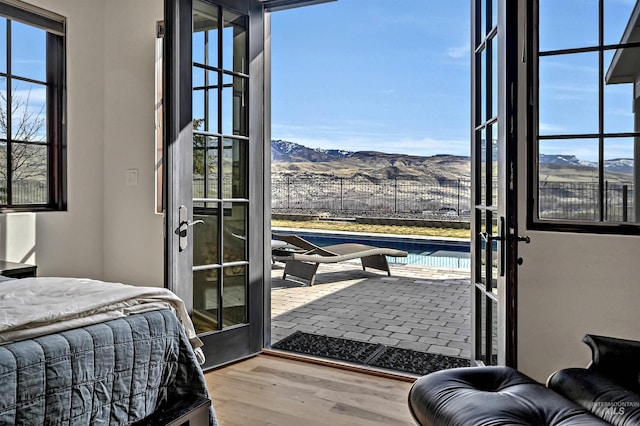 bedroom with multiple windows, wood finished floors, and a mountain view