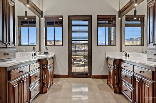 bathroom featuring tile patterned floors, baseboards, and two vanities