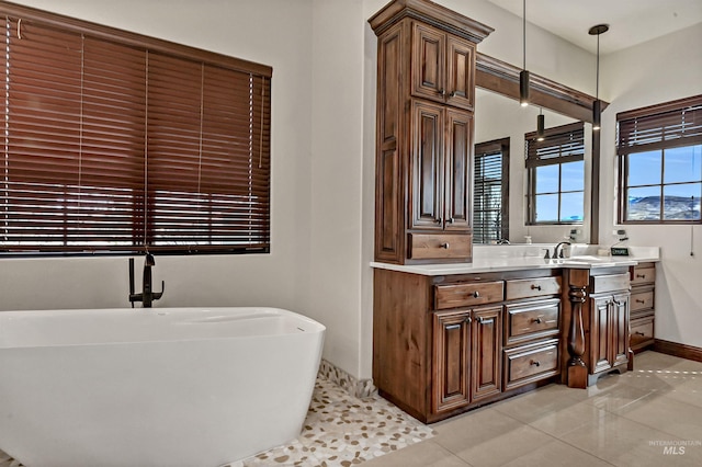 bathroom featuring vanity, a freestanding tub, baseboards, and tile patterned flooring