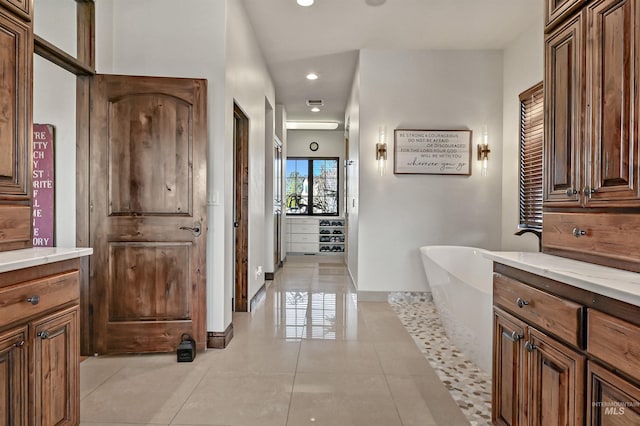 bathroom with tile patterned flooring, a soaking tub, recessed lighting, and baseboards