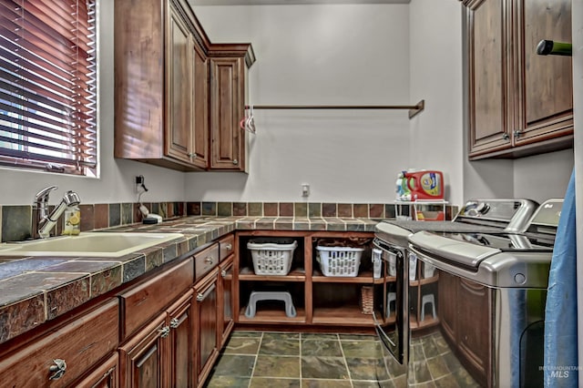 washroom featuring stone finish floor, cabinet space, independent washer and dryer, and a sink