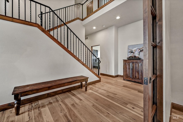 entrance foyer featuring baseboards, stairway, recessed lighting, a high ceiling, and wood finished floors