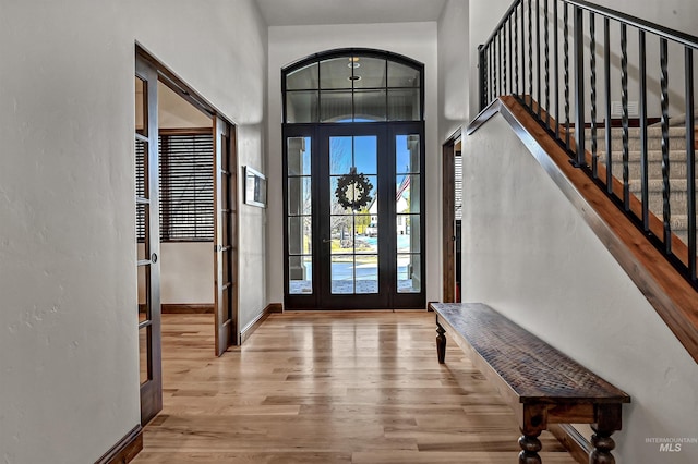 entryway featuring a high ceiling, stairs, baseboards, and wood finished floors