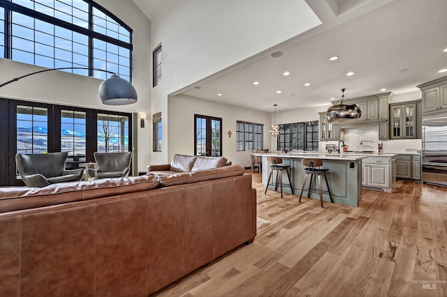 living area featuring light wood-style flooring, recessed lighting, and a high ceiling