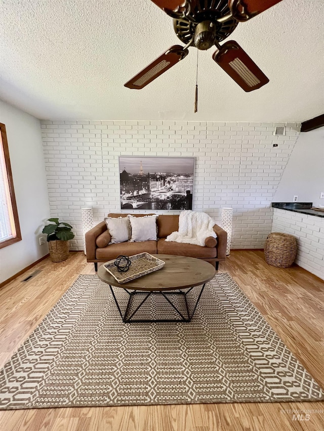 2025 10th Ave, Clarkston, WA 99403 - living room featuring a textured ceiling, wood finished floors, a ceiling fan, and brick wall
