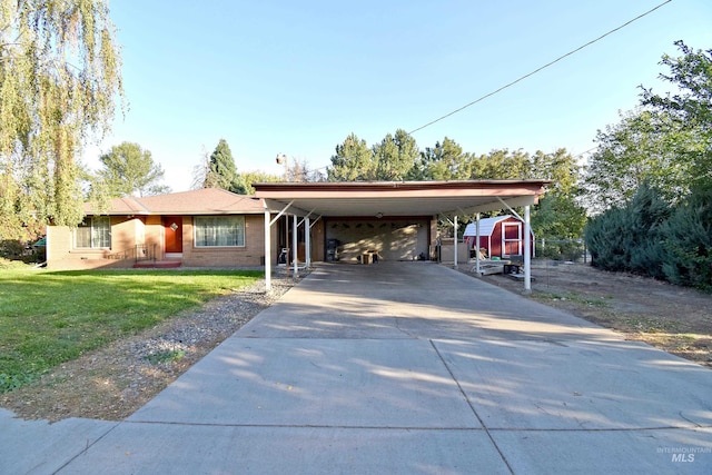 view of front facade featuring a carport, a storage unit, and a front yard