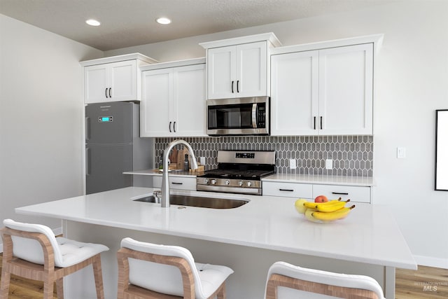 kitchen with a breakfast bar, tasteful backsplash, stainless steel appliances, and a sink