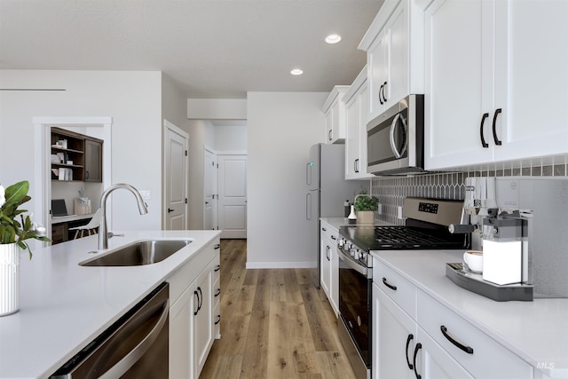 kitchen featuring stainless steel appliances, a sink, white cabinets, light countertops, and decorative backsplash