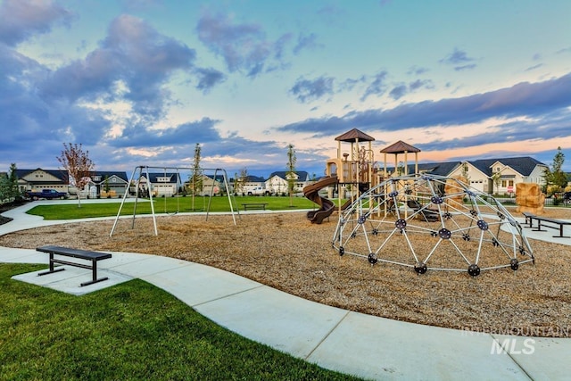 playground at dusk with playground community, a yard, and a residential view