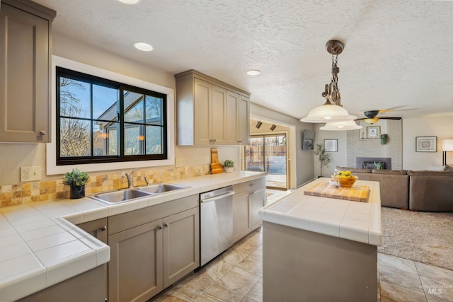 kitchen featuring a fireplace, stainless steel dishwasher, open floor plan, a kitchen island, and a sink