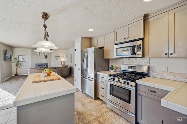 kitchen with tile countertops, a kitchen island, appliances with stainless steel finishes, and open floor plan