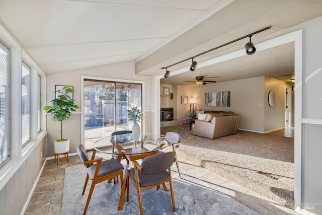 dining area with lofted ceiling, light colored carpet, a fireplace, baseboards, and rail lighting