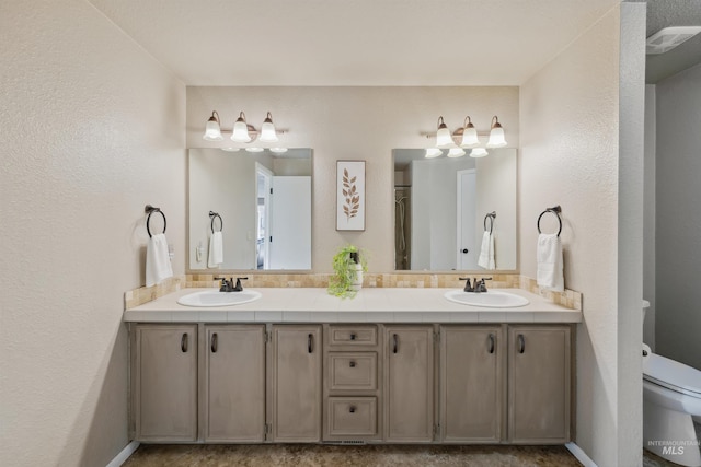 full bath featuring double vanity, a sink, and toilet