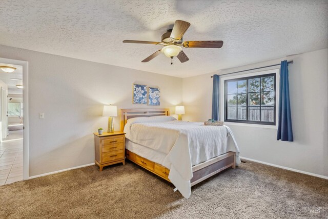 carpeted bedroom featuring a textured ceiling, ceiling fan, and baseboards