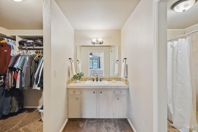 ensuite bathroom featuring a textured ceiling, a textured wall, and connected bathroom