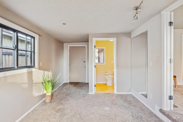 unfurnished room featuring carpet, rail lighting, and baseboards