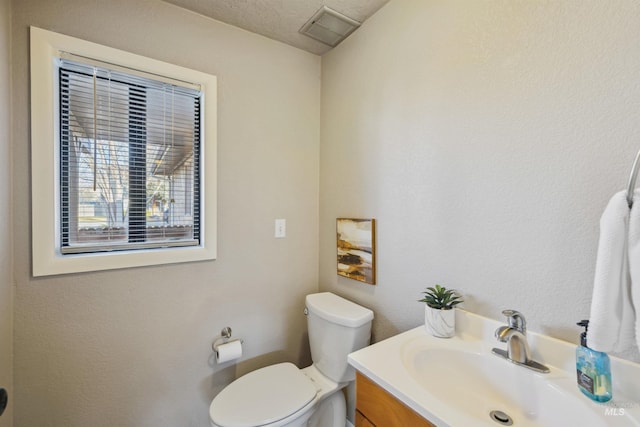 half bathroom with toilet, visible vents, and vanity