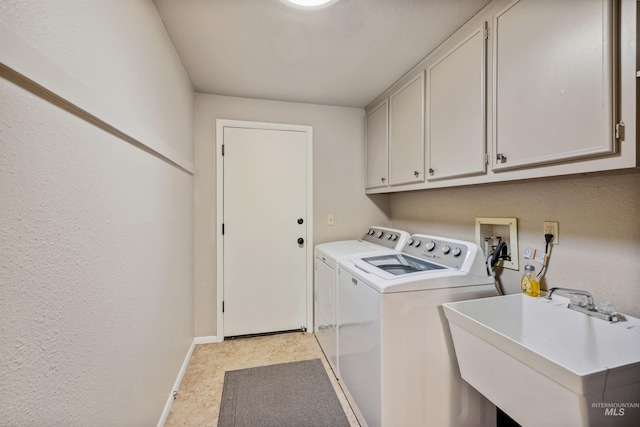 washroom with cabinet space, baseboards, washer and clothes dryer, and a sink