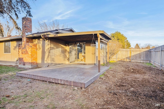 rear view of house featuring a chimney, a fenced backyard, and a wooden deck