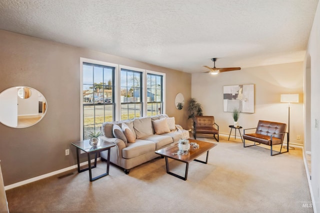 living area featuring a textured ceiling, light colored carpet, a ceiling fan, baseboards, and visible vents