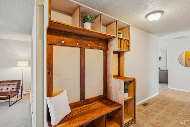 mudroom with a textured ceiling, visible vents, and baseboards