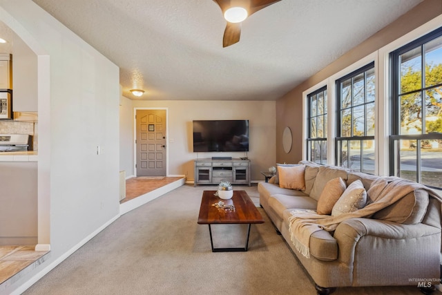 living room featuring a ceiling fan, carpet, a textured ceiling, and baseboards