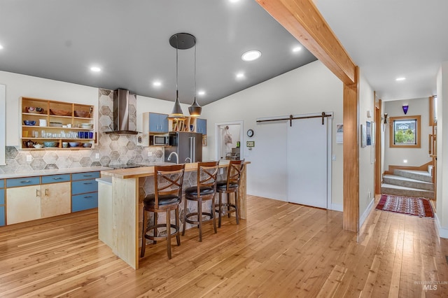 2809 Hampton Ct, Moscow, ID 83843 - kitchen with wall chimney range hood, stainless steel appliances, light wood finished floors, decorative backsplash, and light countertops