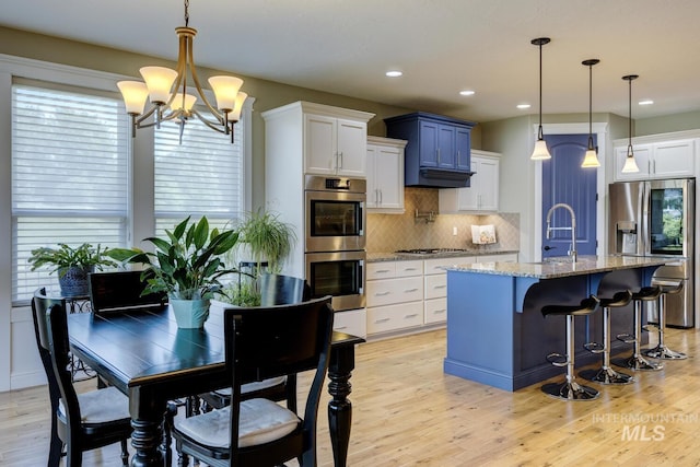 3214 S Arctic Fox Ave, Eagle, ID 83616 - kitchen with appliances with stainless steel finishes, light wood-style floors, a chandelier, decorative backsplash, and recessed lighting